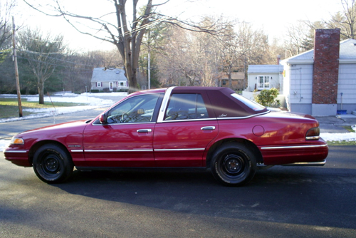 2000 Ford Crown Victoria sedan, side view, red with burgundy vinyl top