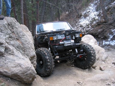 1981 Ford Bronco - This heavily modified off-road vehicle tackles a challenging rocky trail, its extreme suspension and tire setup.