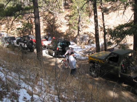1981 Ford Bronco - Multiple off-road vehicles are parked on a snowy trail in a wooded area.