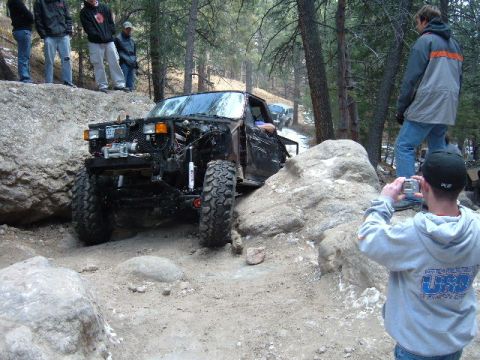 1993 Ford Bronco - This 1993 Ford Bronco is tackling a challenging off-road course with spectators watching.