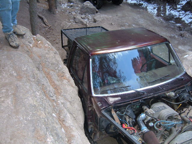 Brown Ford Bronco off-roading, hood open, stuck between rocks