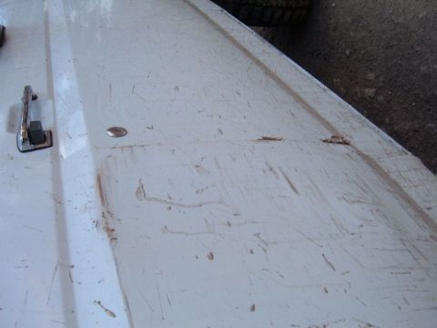 1993 Ford Bronco - Close-up of a white vehicle hood, a handle and visible scratches.