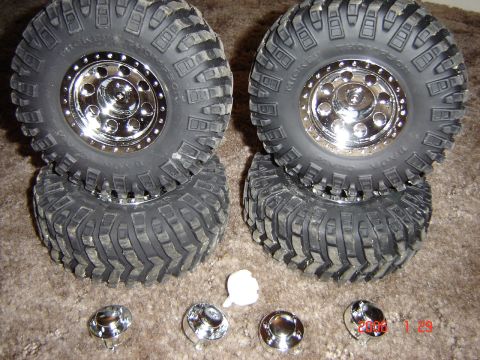 1993 Ford Bronco - A set of four off-road tires and chrome rims are displayed on a carpeted surface.