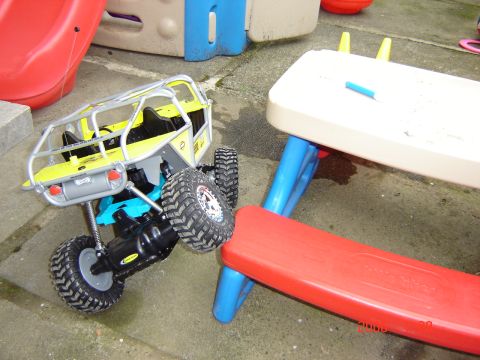 1993 Ford Bronco - A toy rock crawler RC car is positioned on a concrete surface near a child's play table.