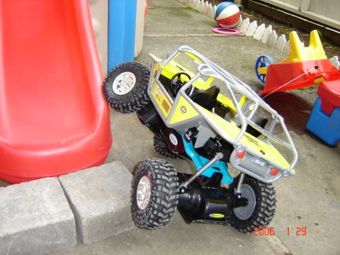 1993 Ford Bronco - A yellow off-road buggy toy is tilted on its side next to a red slide, with large tires visible.