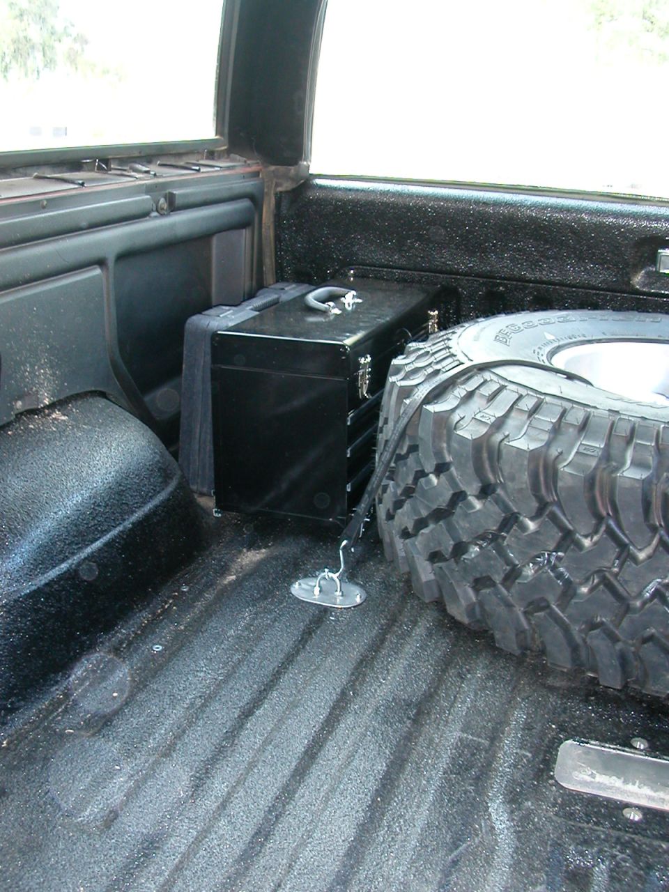 Spare tire and black toolbox secured in the cargo area of a vehicle