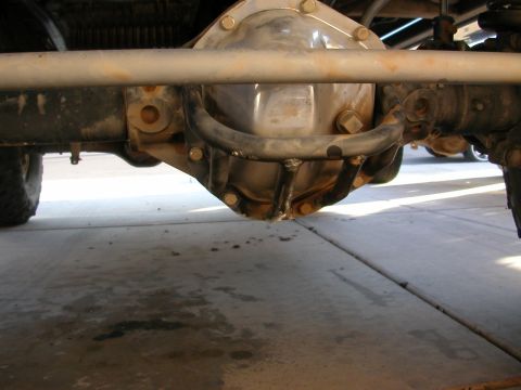 1984 Ford Bronco - Underside view of a vehicle's rear axle and suspension components, with another vehicle visible in the background.