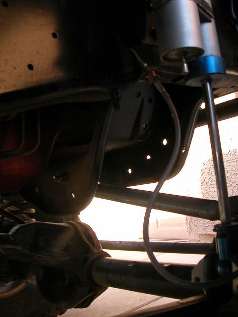 1984 Ford Bronco - Close-up of suspension components, including a shock absorber, on a vehicle's undercarriage.