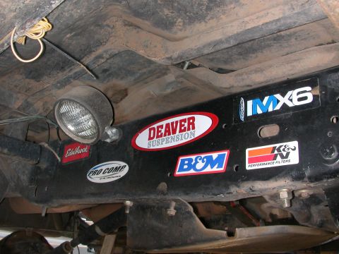 1984 Ford Bronco - Vehicle undercarriage shows various performance part stickers including Deaver, K&N, and Edelbrock.