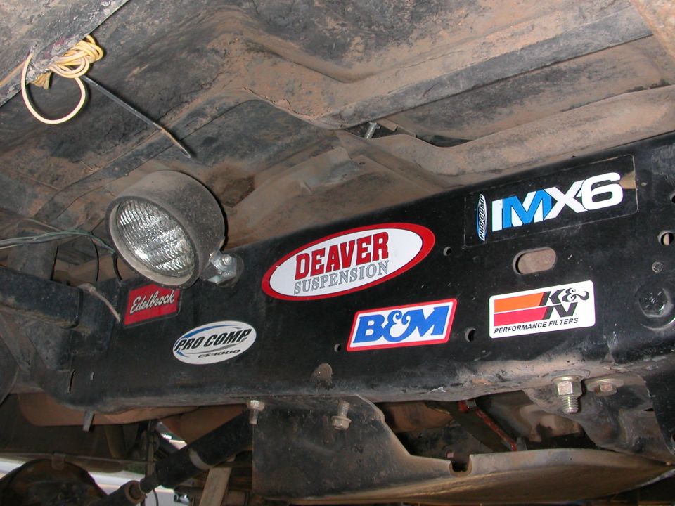 Underbody view of a vehicle frame with Deaver Suspension, K&N Performance Filters, Edelbrock, Pro Comp, B&M, and IMX6 stickers