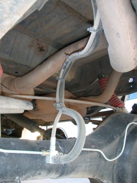 1984 Ford Bronco - Close-up view of the undercarriage, showing exhaust pipes, suspension components, and brake lines.