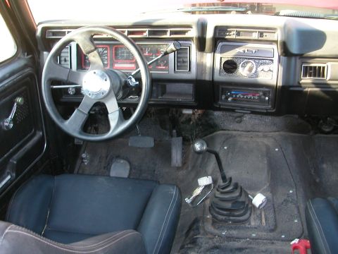 1984 Ford Bronco - The interior of a truck, likely from the early 1980s, features a custom steering wheel and aftermarket radio.