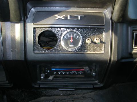 1984 Ford Bronco - Close-up of the interior dashboard, an XLT badge, an amp gauge, and climate controls with temperature and fan settings.