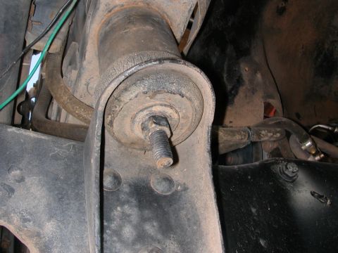 1984 Ford Bronco - A close-up view of a vehicle's suspension system, focusing on a worn bushing and bolt assembly.