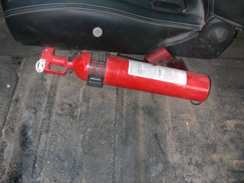 1984 Ford Bronco - A red fire extinguisher is visible on the floor of a vehicle, next to a seat.