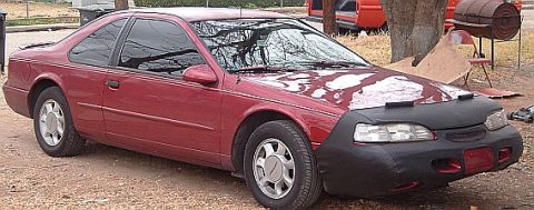 1994 Ford Thunderbird - A red 1994 Ford Thunderbird coupe is parked outside with a car bra covering its front end.