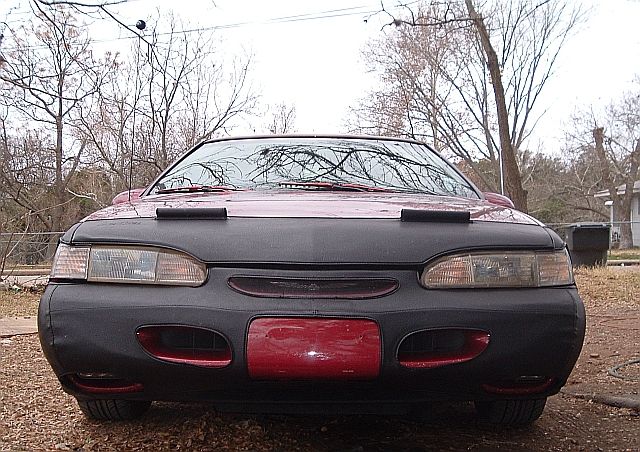 Front view of a red 1994 Ford Thunderbird with a black car bra