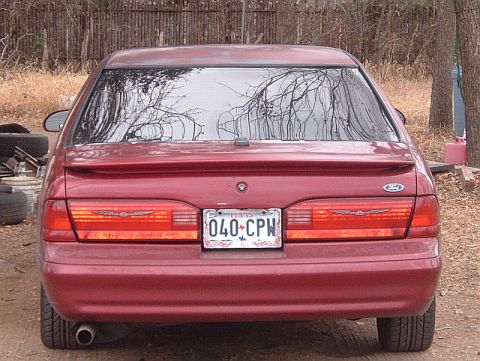 1994 Ford Thunderbird - The rear of a red Ford Thunderbird is shown, its distinctive taillight design and a license plate.