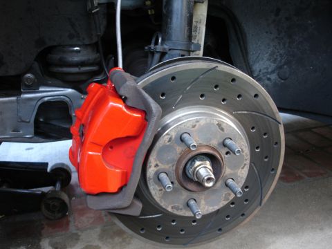 1993 Ford Taurus - Close-up view of a red brake caliper and a drilled and slotted rotor, indicating an upgraded braking system.