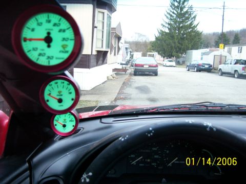 1994 Ford Probe - Interior view of a car's dashboard with gauges, overlooking a residential street scene with parked vehicles.