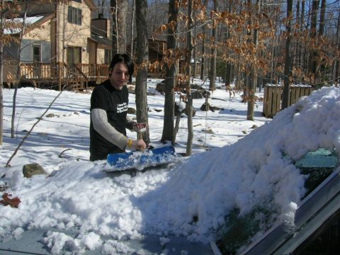 1993 Ford Probe - A person uses a snow brush to clear a car windshield covered in snow, with the Supermotors logo visible on the glass.