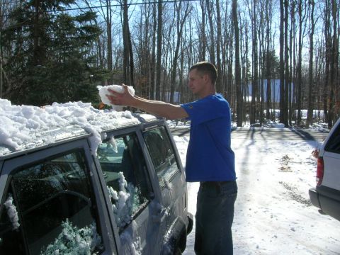 1993 Ford Probe - A man is clearing snow from the roof of an SUV on a sunny winter day.