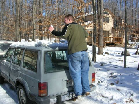 1993 Ford Probe - A person stands on the bumper of a Jeep Cherokee XJ covered in snow, holding a snowball.
