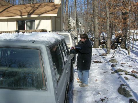 1993 Ford Probe - A person uses a snow brush on the side of a gray SUV parked in a snowy driveway.