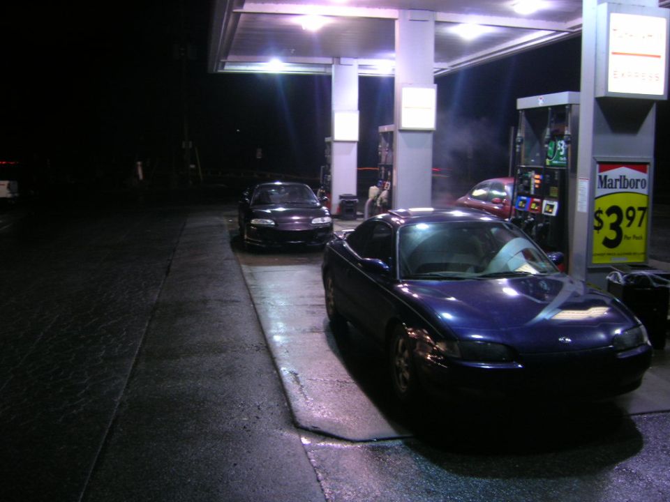 Blue 1993 Ford Probe parked at a gas station at night, front 3/4 view