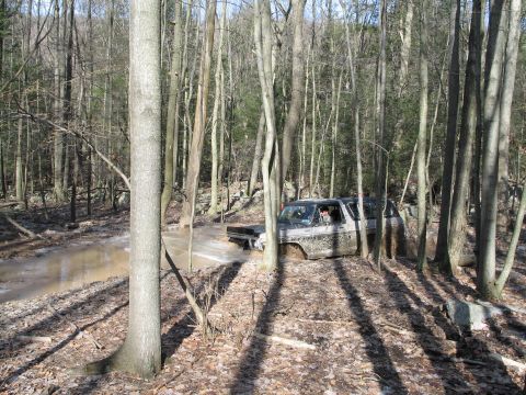 1995 Ford Bronco - This Ford Bronco is navigating a muddy stream in a wooded area.