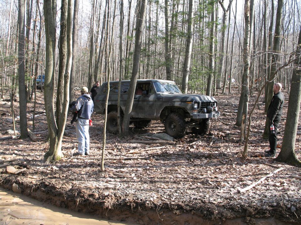 off-road SUV with winch in woods, another vehicle in background