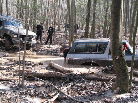 1995 Ford Bronco - Two off-road vehicles are stuck in the mud while navigating a wooded trail.
