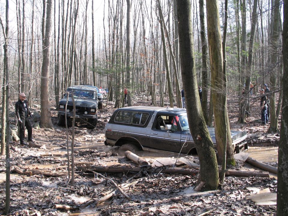 Brown and silver Ford Bronco stuck in mud, side view
