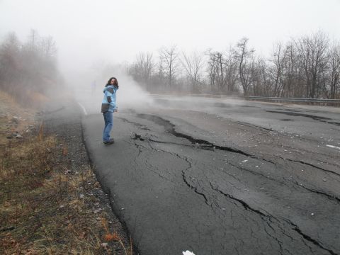 1995 Ford Bronco - A person stands on a damaged road with steam billowing around them on a foggy day.