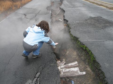 1995 Ford Bronco - A person examines a significant fissure in the asphalt, with steam emanating from the exposed ground below.