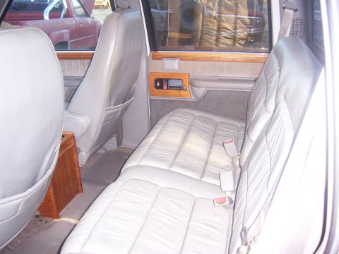 1992 Ford C-250 (Centurion Conversions) - Rear interior of a van, plush leather seats and wood accents. Another vehicle is visible through the window.