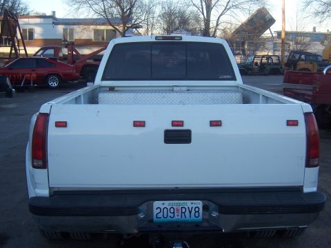 1992 Ford C-250 (Centurion Conversions) - This white pickup truck is parked in an outdoor lot with other vehicles and buildings in the background.