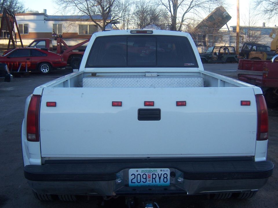 Rear of white dually pickup with Missouri plate in a gravel junk lot