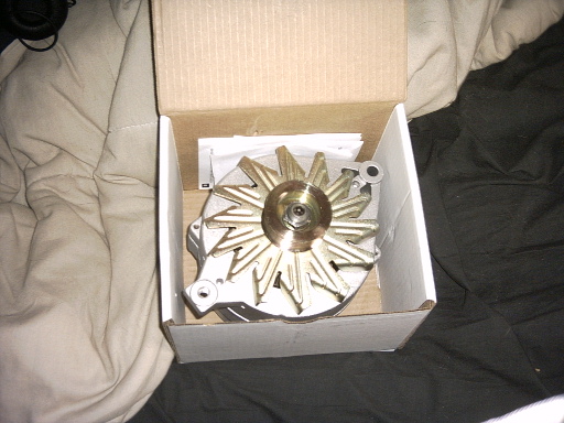 New alternator with gold cooling fan sitting in an open cardboard box