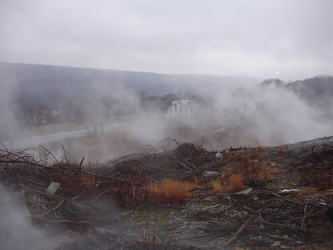 1979 Ford Bronco - A hazy scene unfolds over a landscape dotted with buildings and obscured by fog, with debris scattered across the foreground.