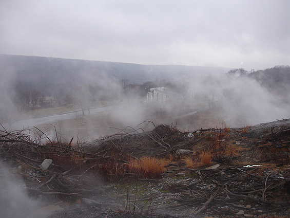 Steam venting from barren ground on a smoky hillside overlook