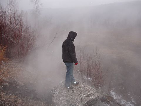 1979 Ford Bronco - A person surveys a misty, desolate environment from a rocky outcrop.
