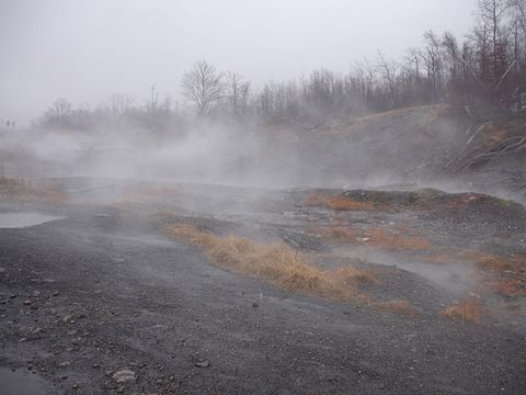 1979 Ford Bronco - Steam or fog drifts across a barren gray strip-mine landscape of coal spoil, gravel and dead brown grass, with bare winter trees on the rid…
