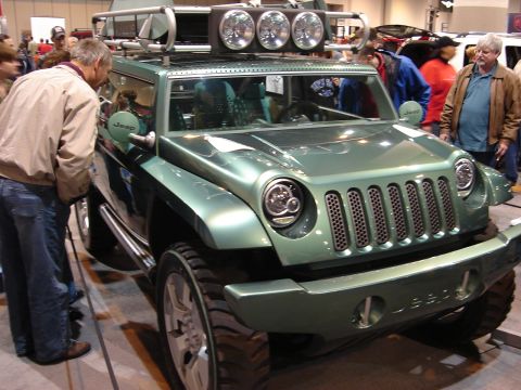 2000 Ford Crown Victoria - A green Jeep concept vehicle is on display indoors, with several people observing it.