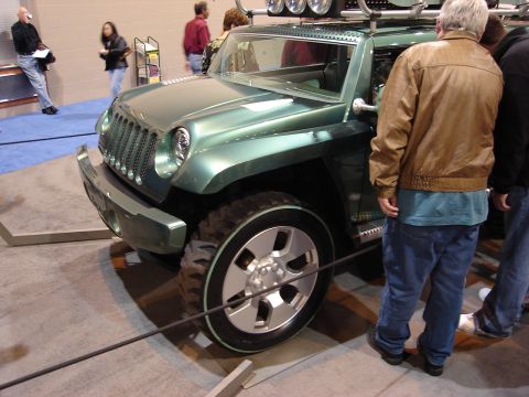2000 Ford Crown Victoria - A green Jeep Wrangler concept vehicle is displayed at an auto show, with onlookers observing.