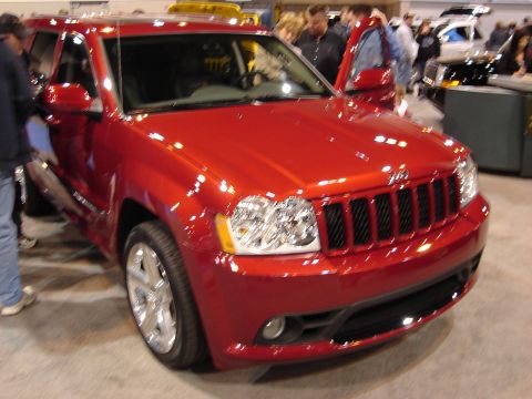 2000 Ford Crown Victoria - Red Jeep Grand Cherokee on display at an auto show, showing its distinctive grille.