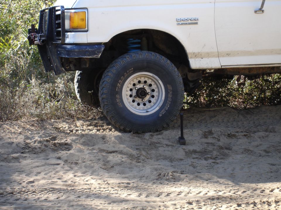 White 1989 Ford Bronco front fender and tire with off-road modifications
