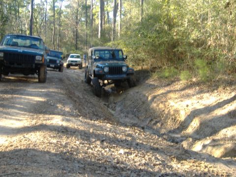 1999 Jeep Wrangler - A group of Jeeps, including a green Wrangler, tackle a challenging muddy off-road course.