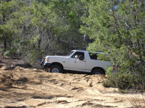1989 Ford Bronco - White 1989 Ford Bronco navigates a sandy off-road path.