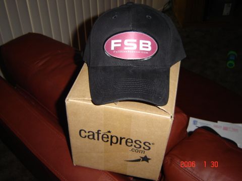 1993 Ford Bronco - A black baseball cap with an oval logo sits on top of a cardboard box with a logo.
